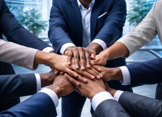 Black entrepreneurs stacking hands in a futuristic office with a team leader at the center