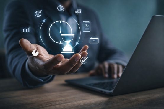 Black professional using a laptop with digital time management and productivity icons floating above hand