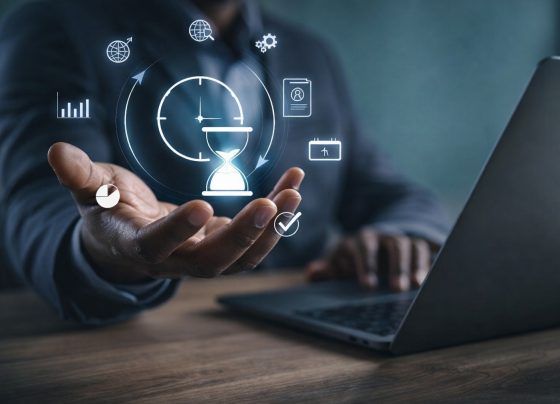 Black professional using a laptop with digital time management and productivity icons floating above hand